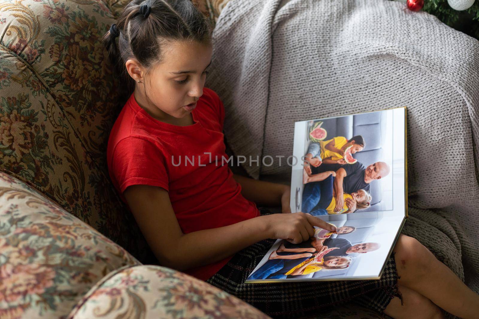 A Little Caucasian girl holding a photobook with her photographs in her hands.