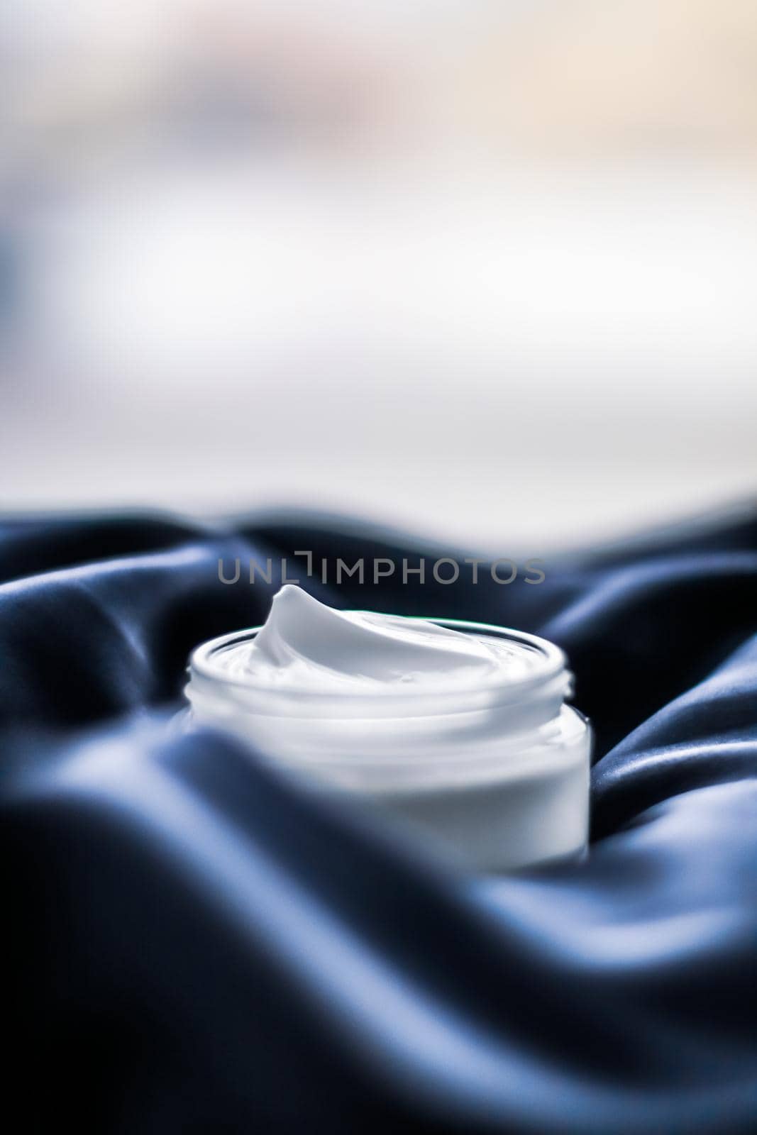 Beauty, anti-age cosmetics and skincare concept - Luxury face cream jar on a dark blue silk