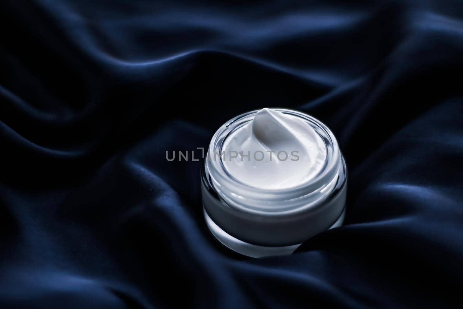 Beauty, anti-age cosmetics and skincare concept - Luxury face cream jar on a dark blue silk