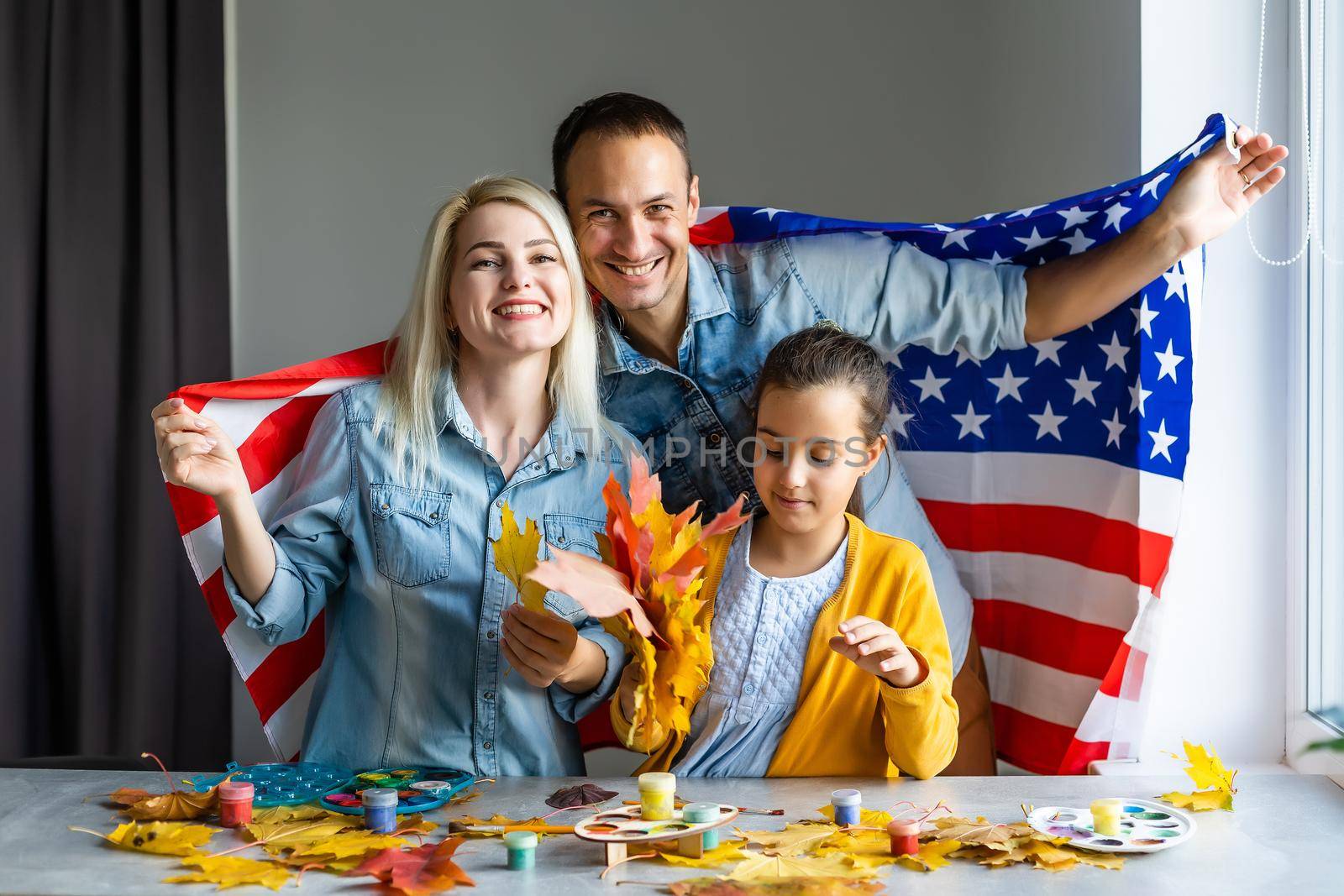 family holding american flag around autumn leaves
