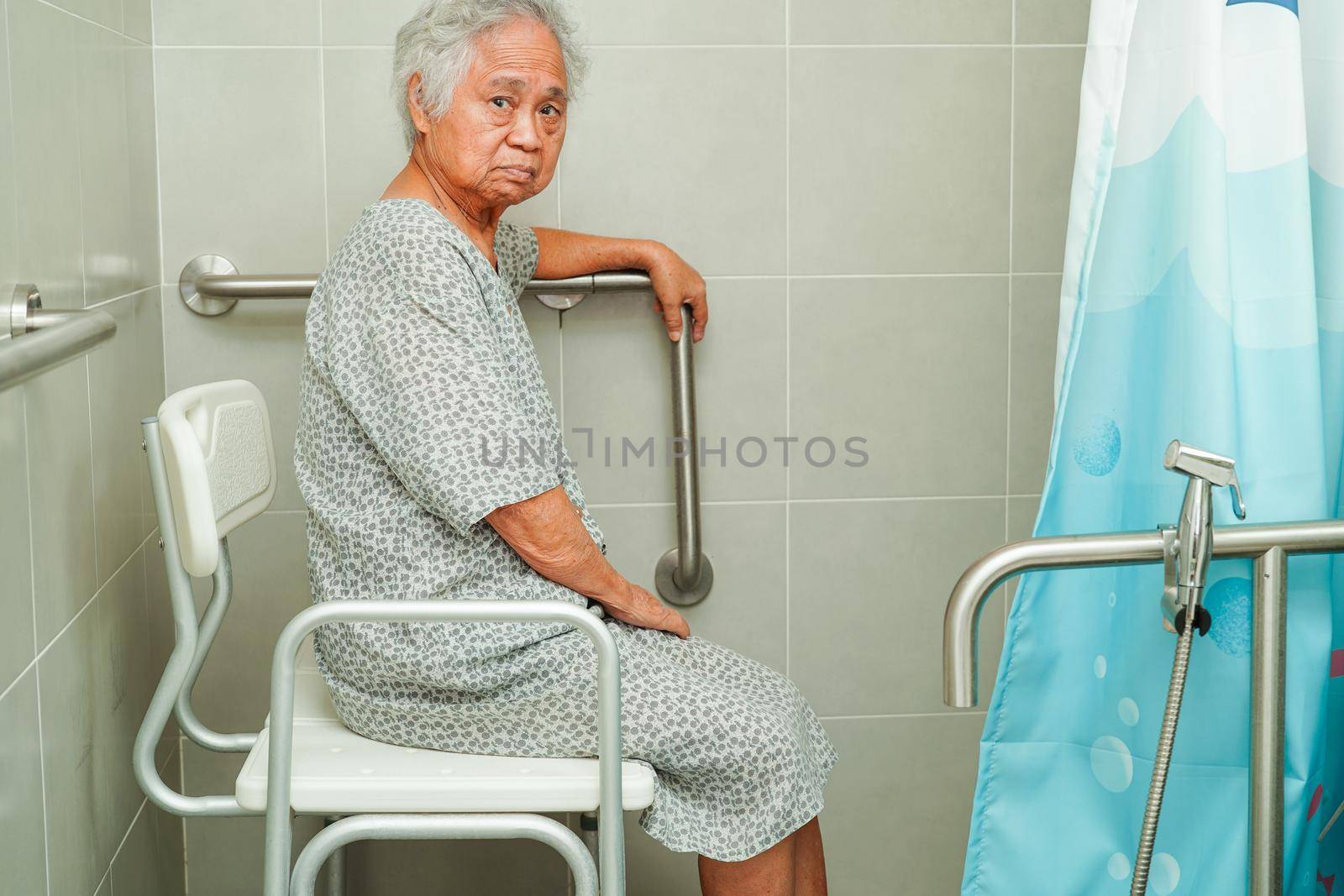 Asian elderly old woman patient use toilet support rail in bathroom, handrail safety grab bar, security in nursing hospital.