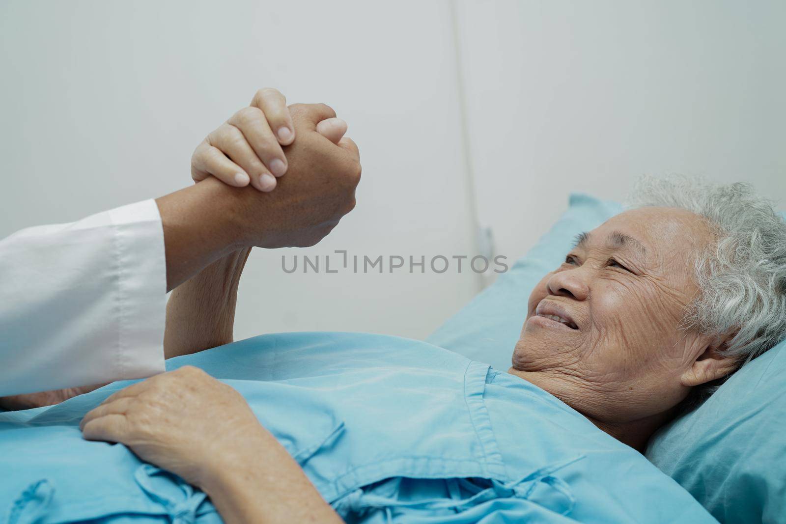 Doctor holding hands Asian elderly woman patient, help and care in hospital.
