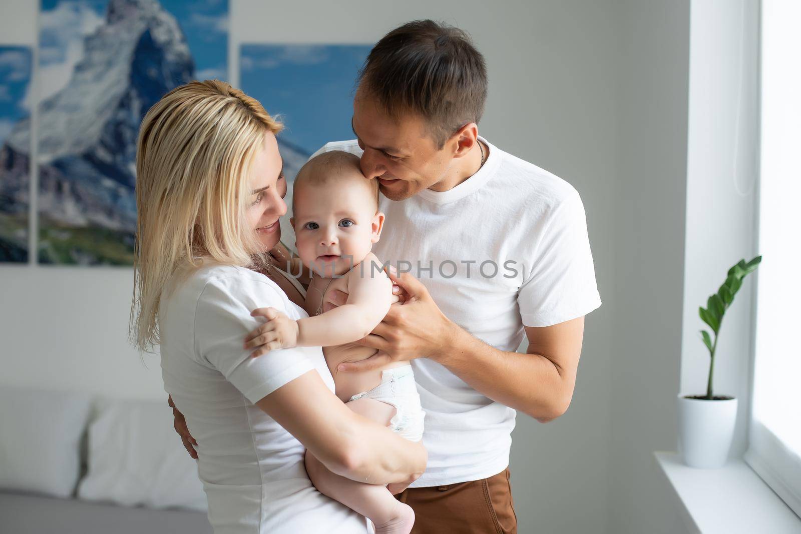 A Happy young family with baby in white bedroom.