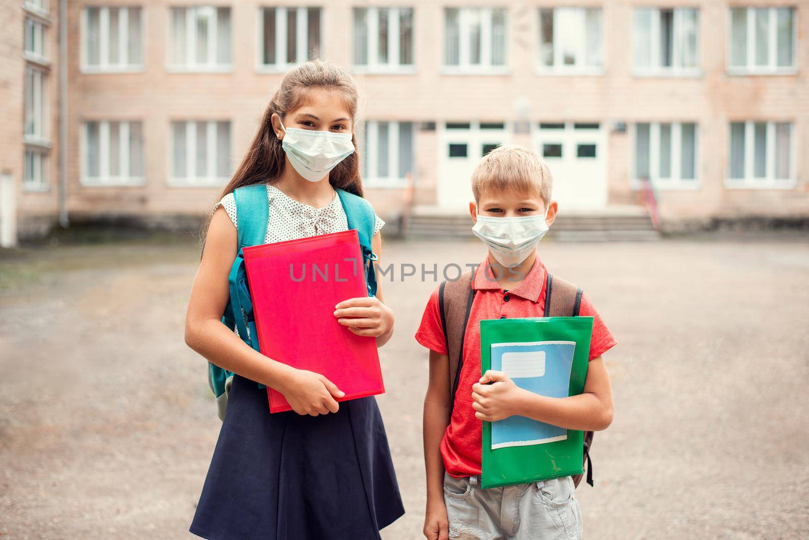 School learners of different age in front of conventional school in medical masks by VitaliiPetrushenko