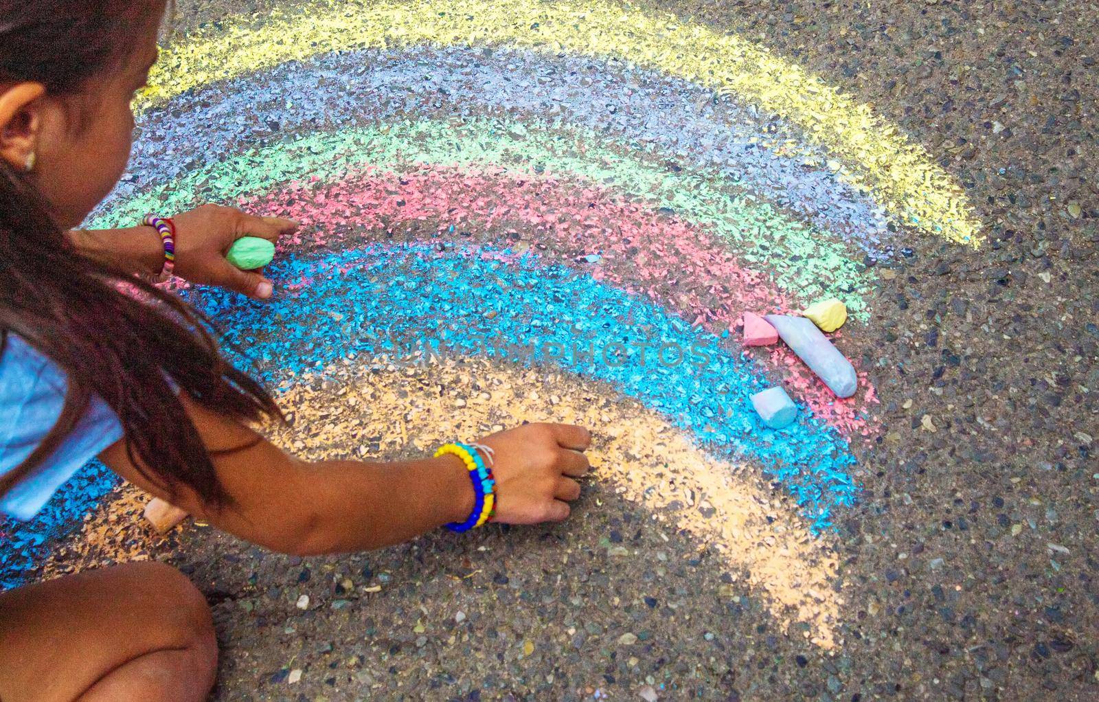 A child draws a rainbow on the asphalt. Selective focus. kid.