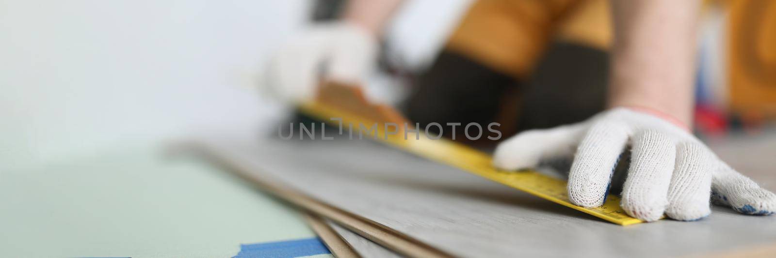 Man builder measuring laminate board with ruler for laying floor closeup. Finishing concept