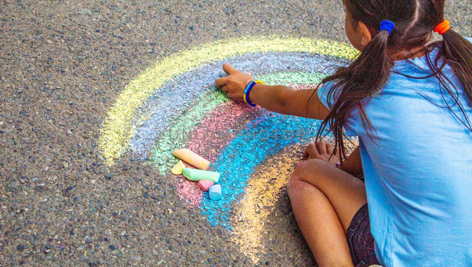 A child draws a rainbow on the asphalt. Selective focus. kid.