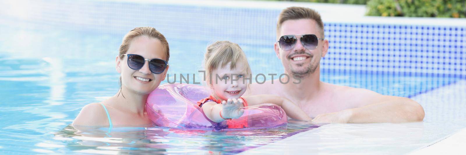 Young family with child in circle in pool on vacation by kuprevich
