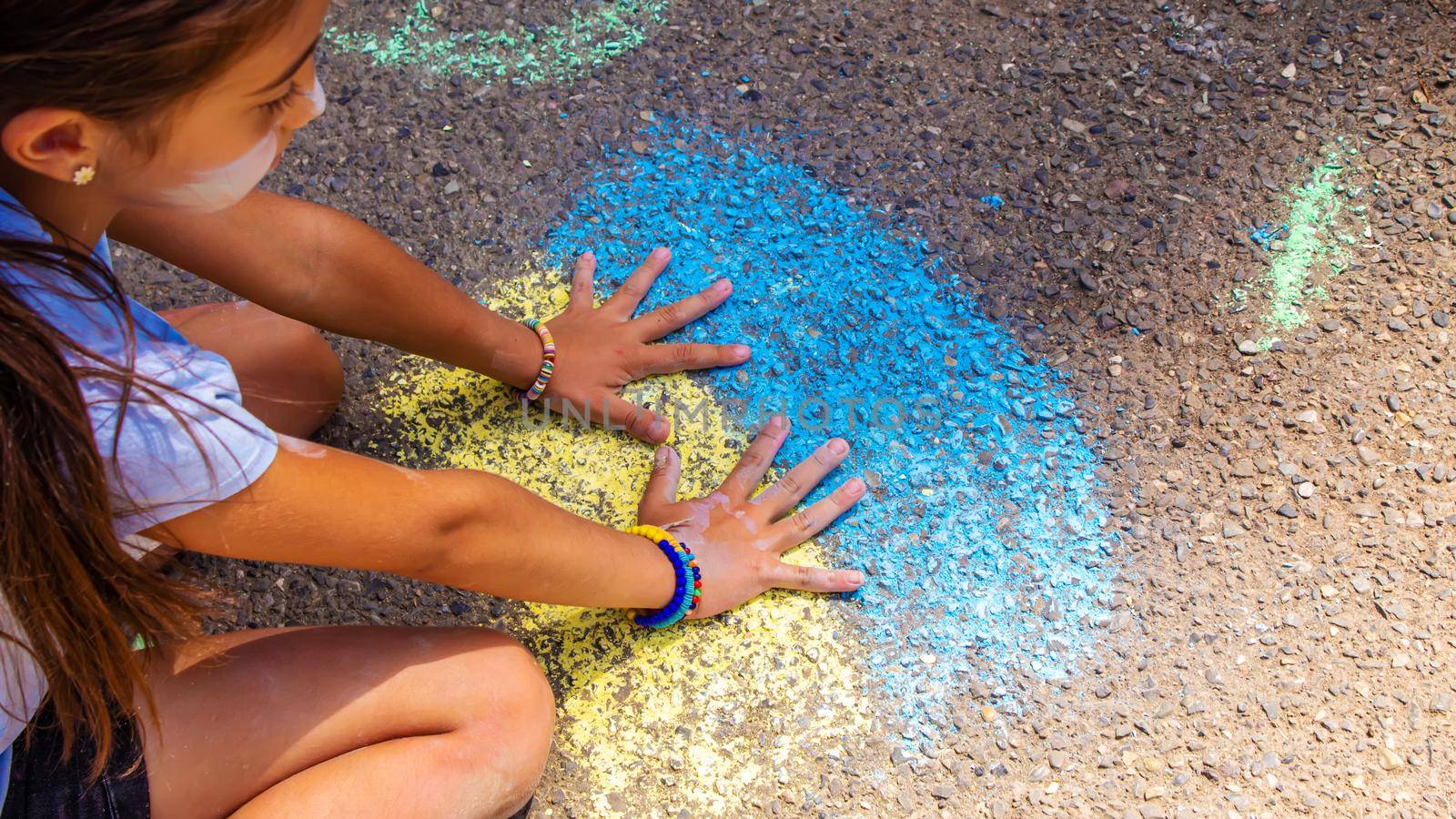 Children paint a rainbow on the asphalt. Selective focus. by mila1784