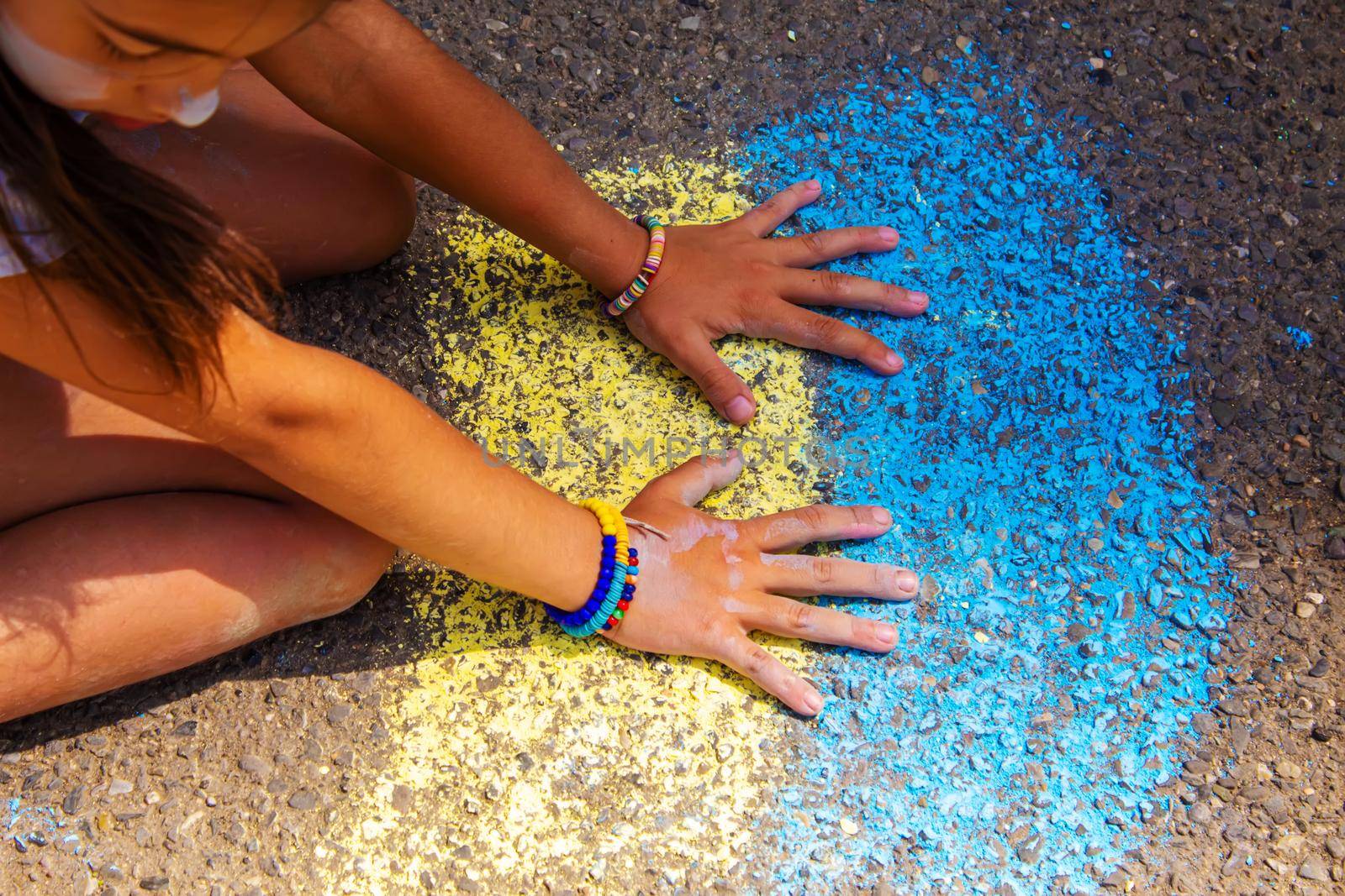 Children paint a rainbow on the asphalt. Selective focus. by mila1784