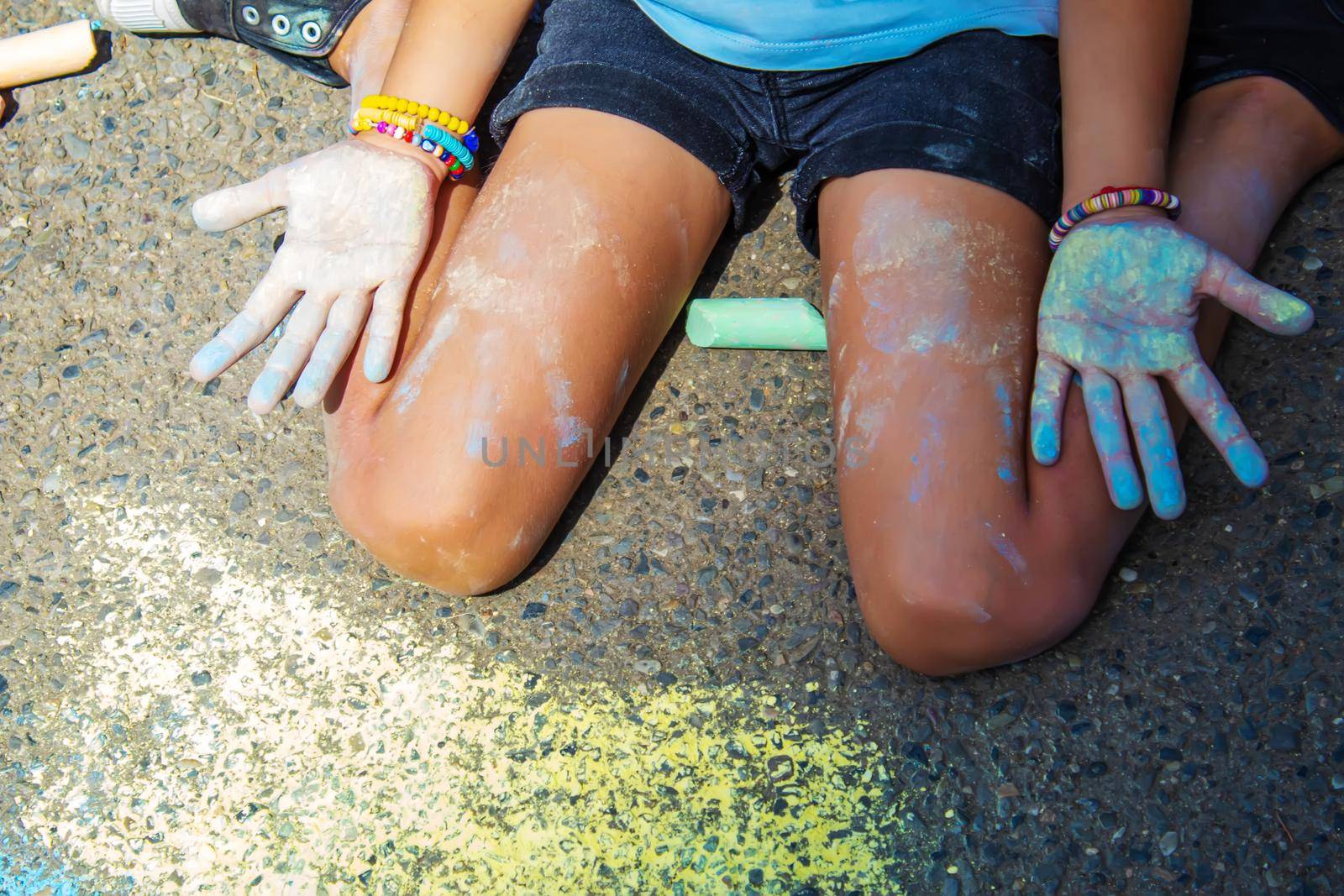 Children paint a rainbow on the asphalt. Selective focus. Kids.