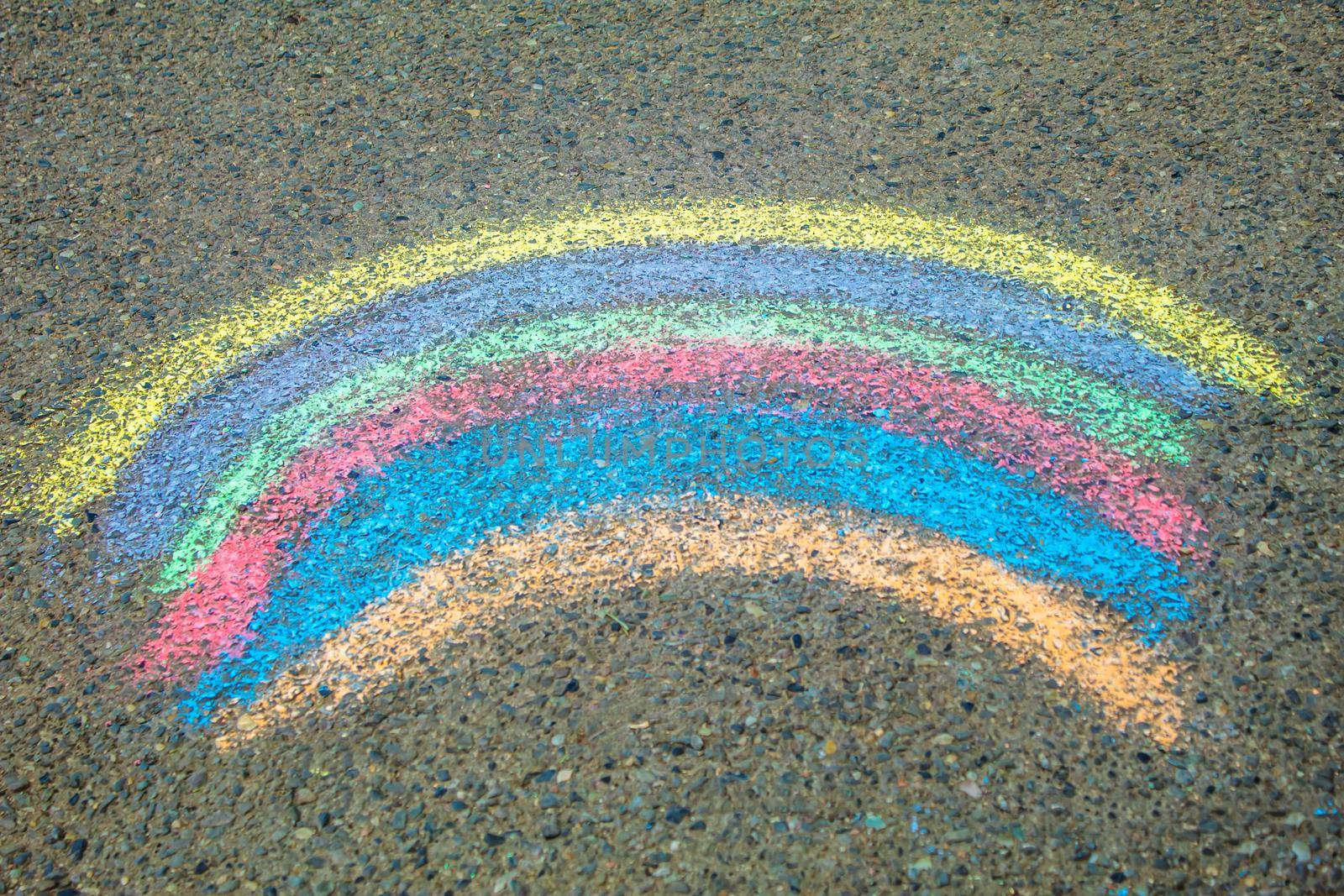 Children paint a rainbow on the asphalt. Selective focus. Kids.