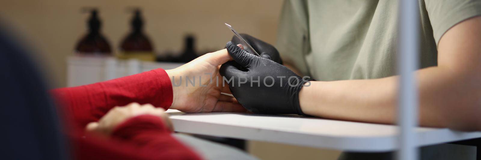 Woman master doing manicure to client in beauty salon by kuprevich