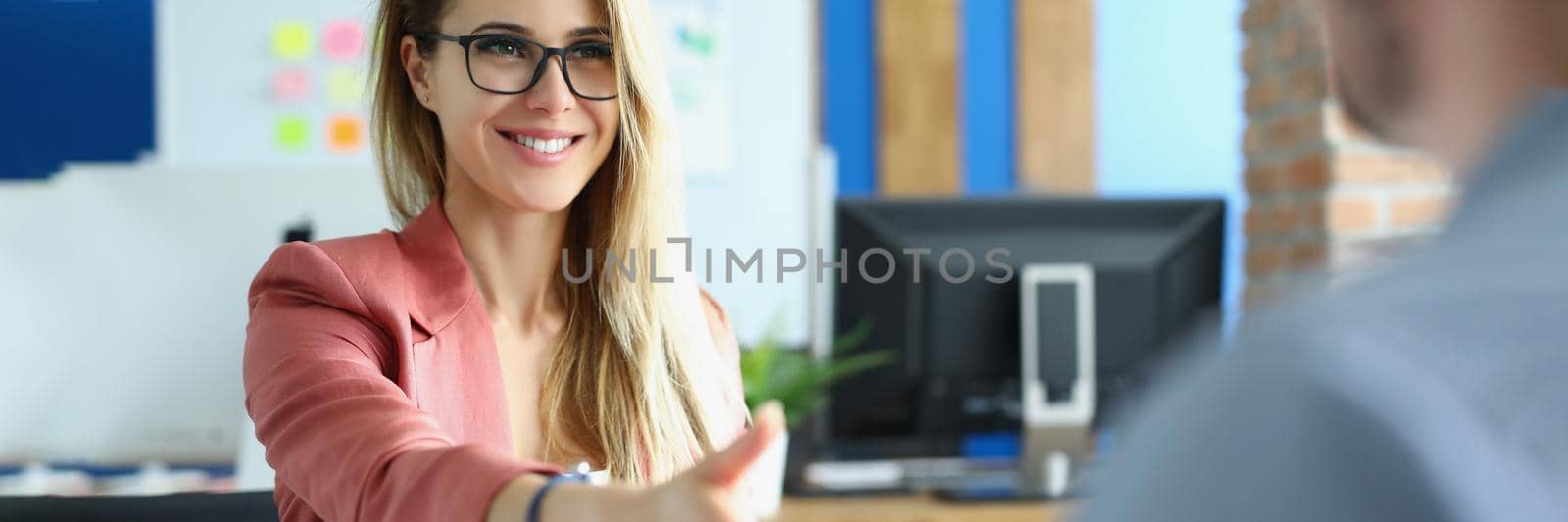 Businesswoman with glasses giving her hand for handshake to her partner. Teamwork concept