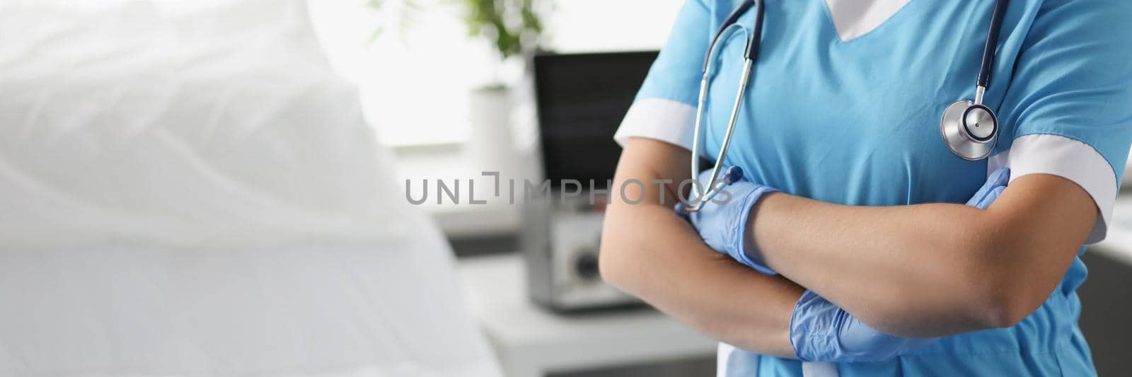 Woman doctor with crossed arms standing in hospital ward closeup. Severe patient care concept