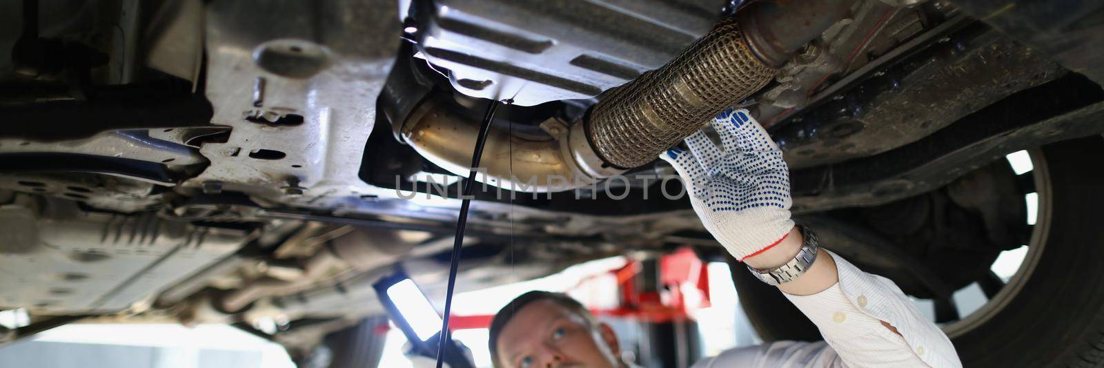 Man repairman fixing car in workshop closeup by kuprevich