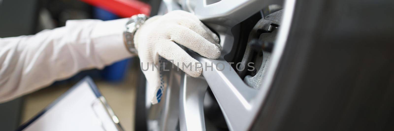 Master repairman holding documents and looking at quality of tires closeup. Car breakdown diagnostics concept