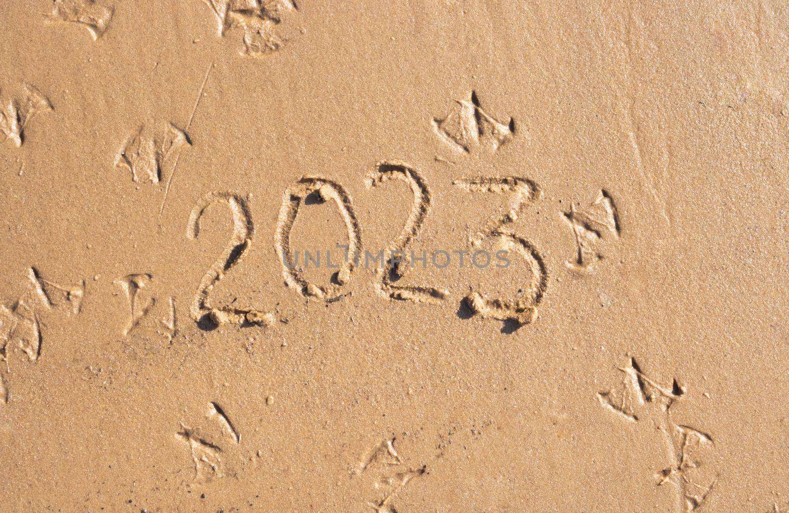 The numbers 2023 are written on the sand on the beach. The concept of the New Year. Happy New Year 2023 background. Travel during the Christmas holidays.