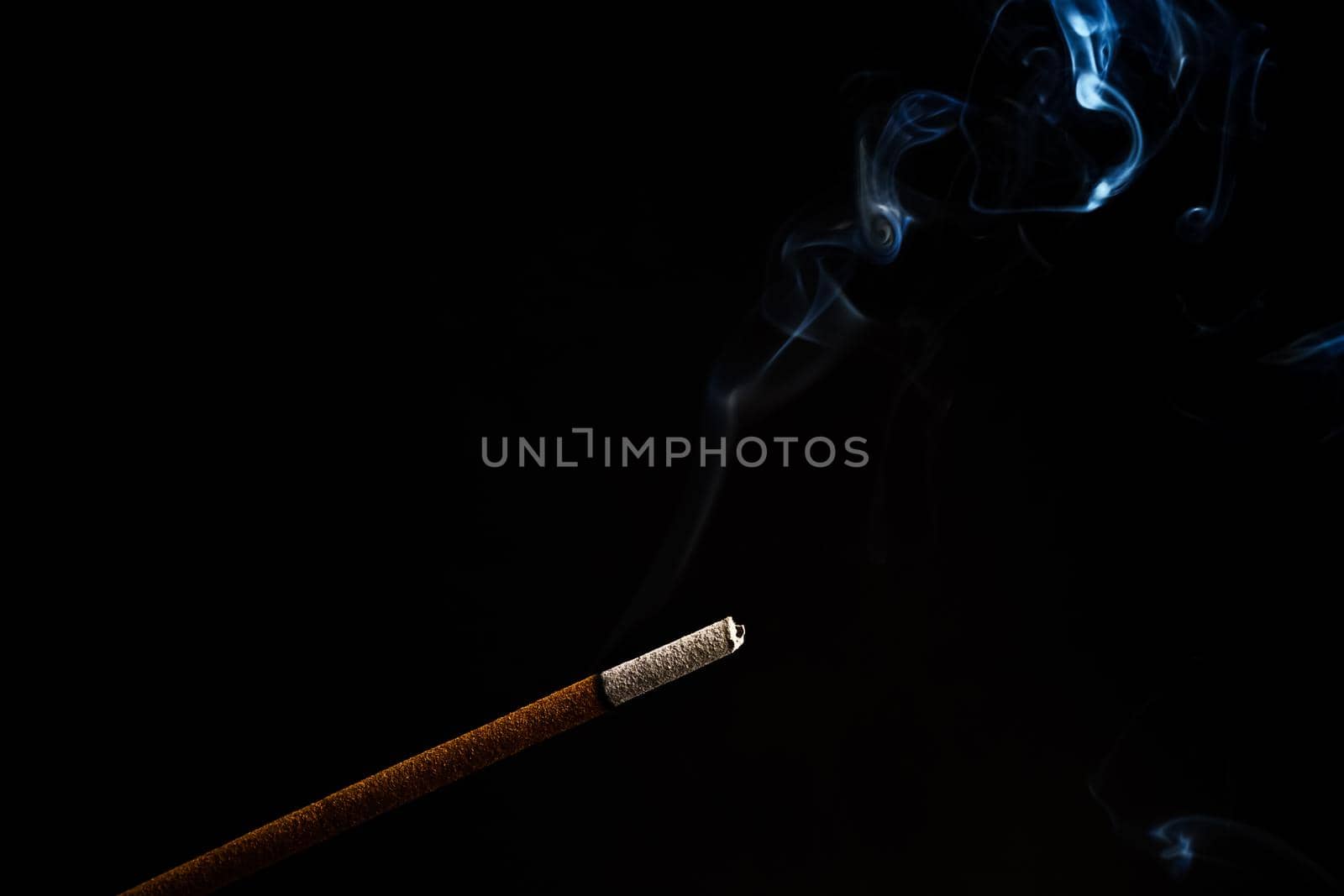 burning incense rising in smoke on a black background by joseantona