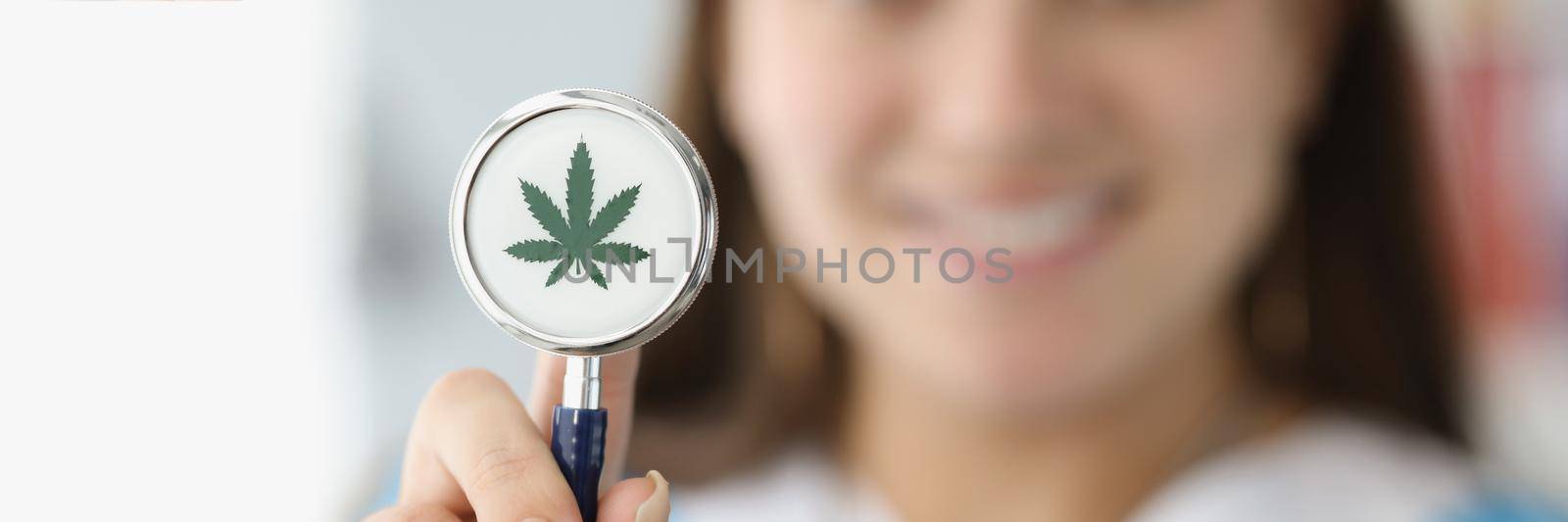 Doctor holding stethoscope with drawn marijuana leaf closeup. Narcotic drug treatment concept