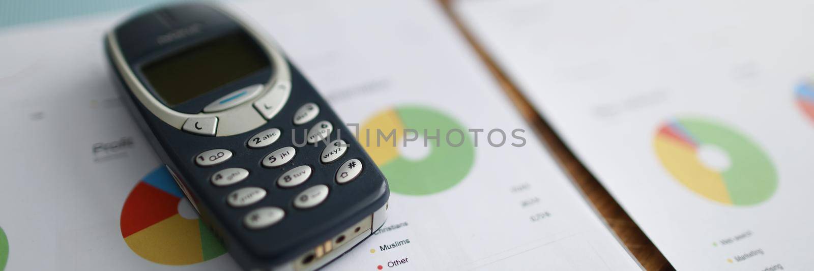 Minsk, Belarus- September 19, 2019: Nokia 3310 mobile phone lying on documents with graphs closeup. Classic business scheme concept