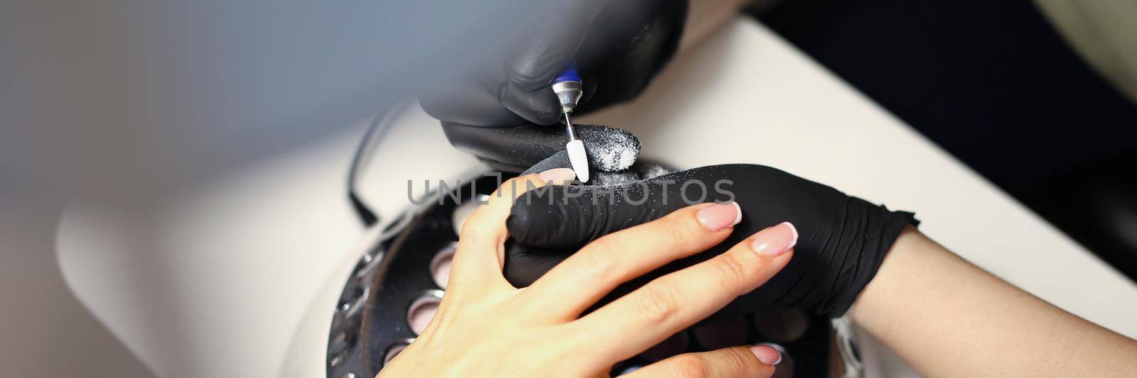Woman master making manicure to client using special machine in beauty salon closeup. Beauty industry concept