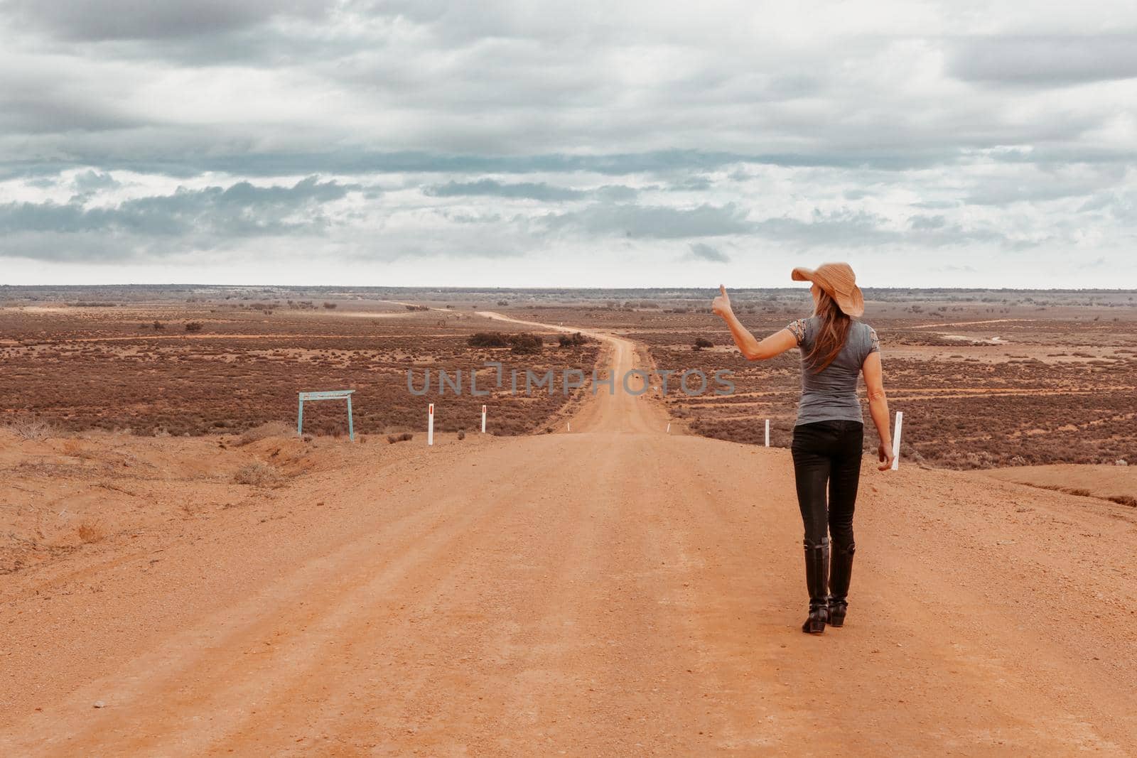 A female on a long dusty road to nowhere with dried up lakes in the desert of Australia by lovleah