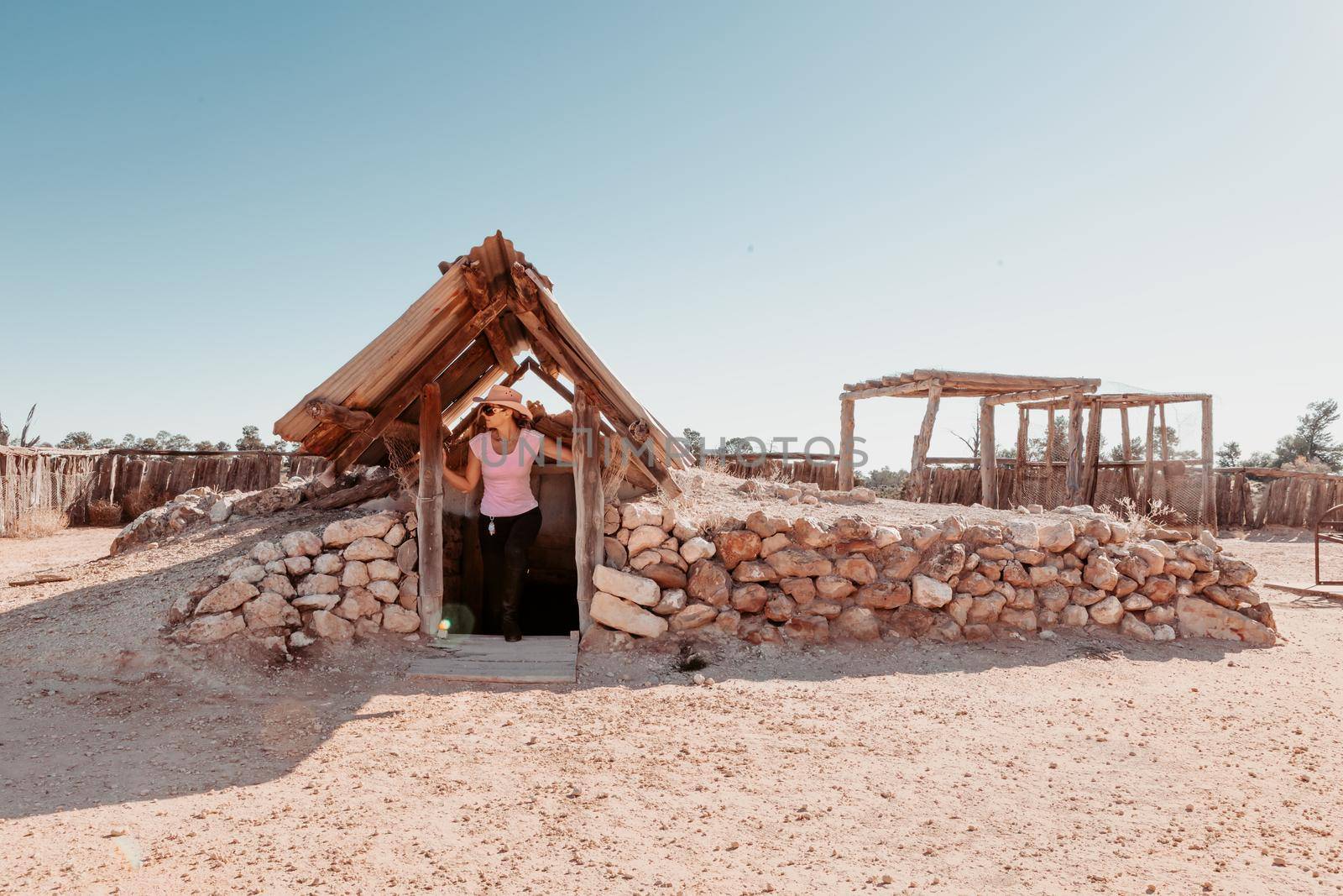 A woman emerging from a simple home built underground in desert Australia by lovleah