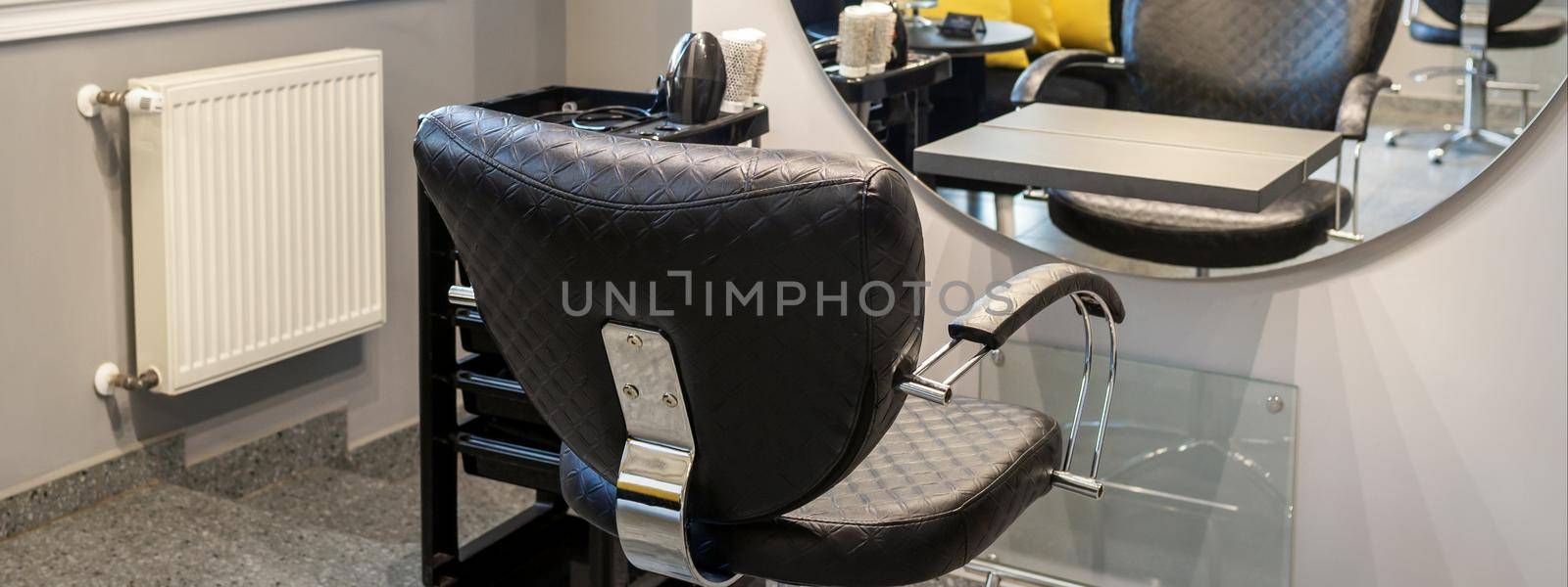 Interior of a beauty salon. Black leather chair in front of the mirror in the beauty salon. Interior of a beauty salon