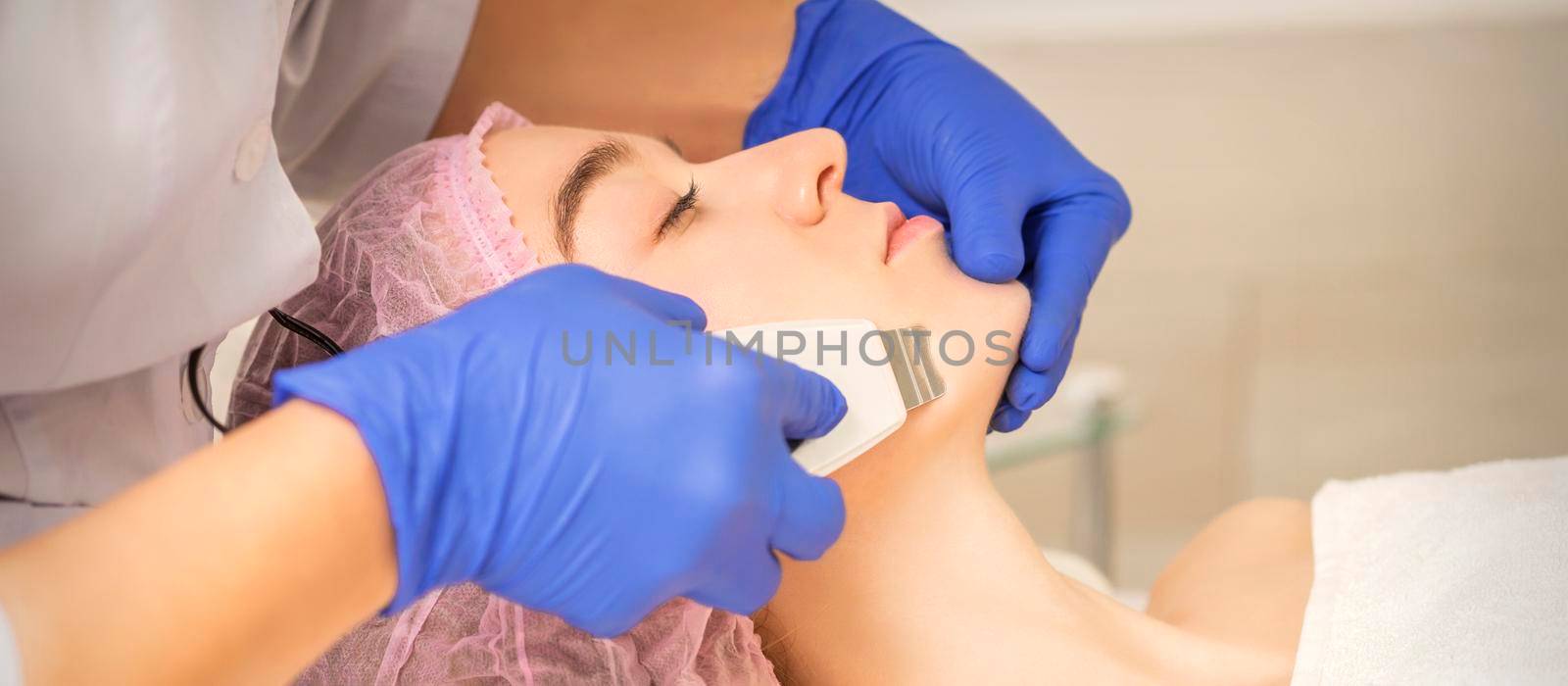 Woman receiving ultrasonic facial cleansing by okskukuruza