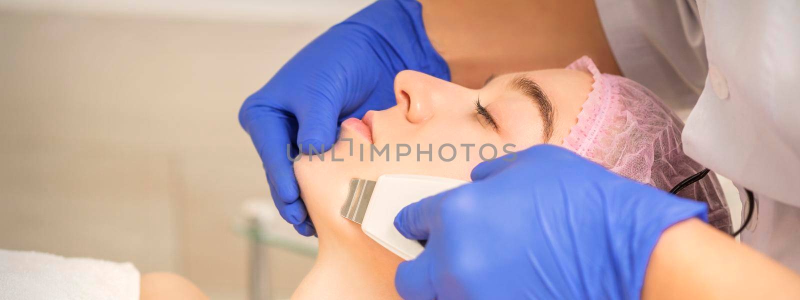 Beautiful young woman receiving ultrasonic cavitation facial cleansing in beauty spa salon