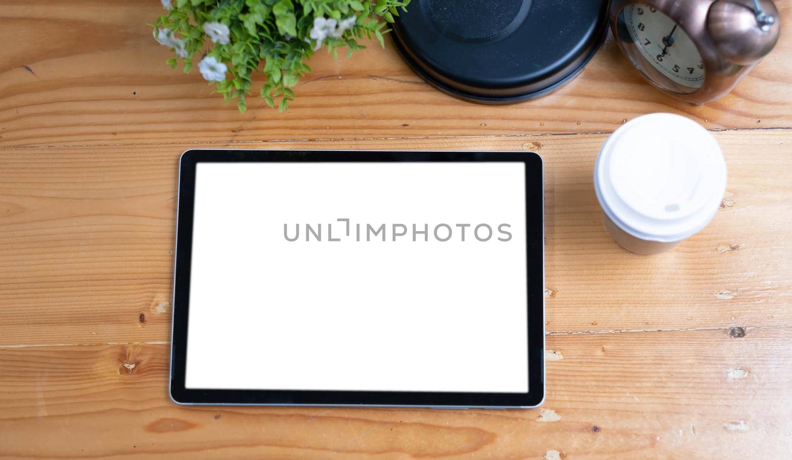 Blank screen tablet and coffee cup on black leather desk background in dark stylish workplace, top view with copy space.