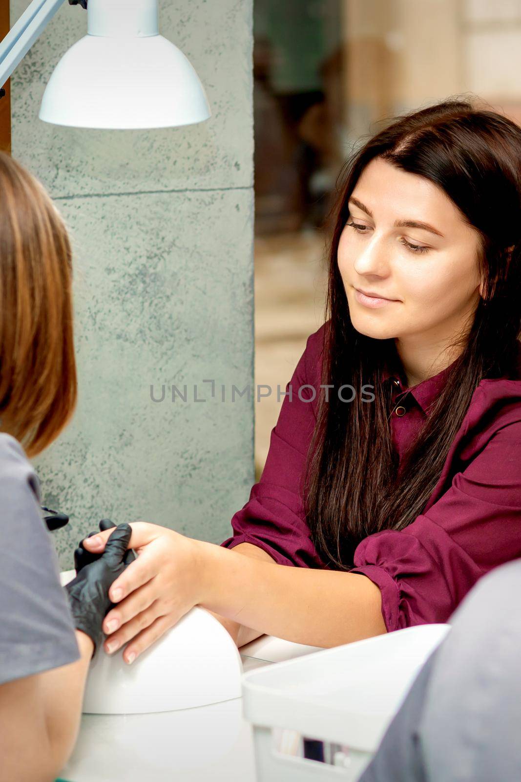 Beautiful young caucasian woman receiving nail treatment sitting in a beauty nail salon