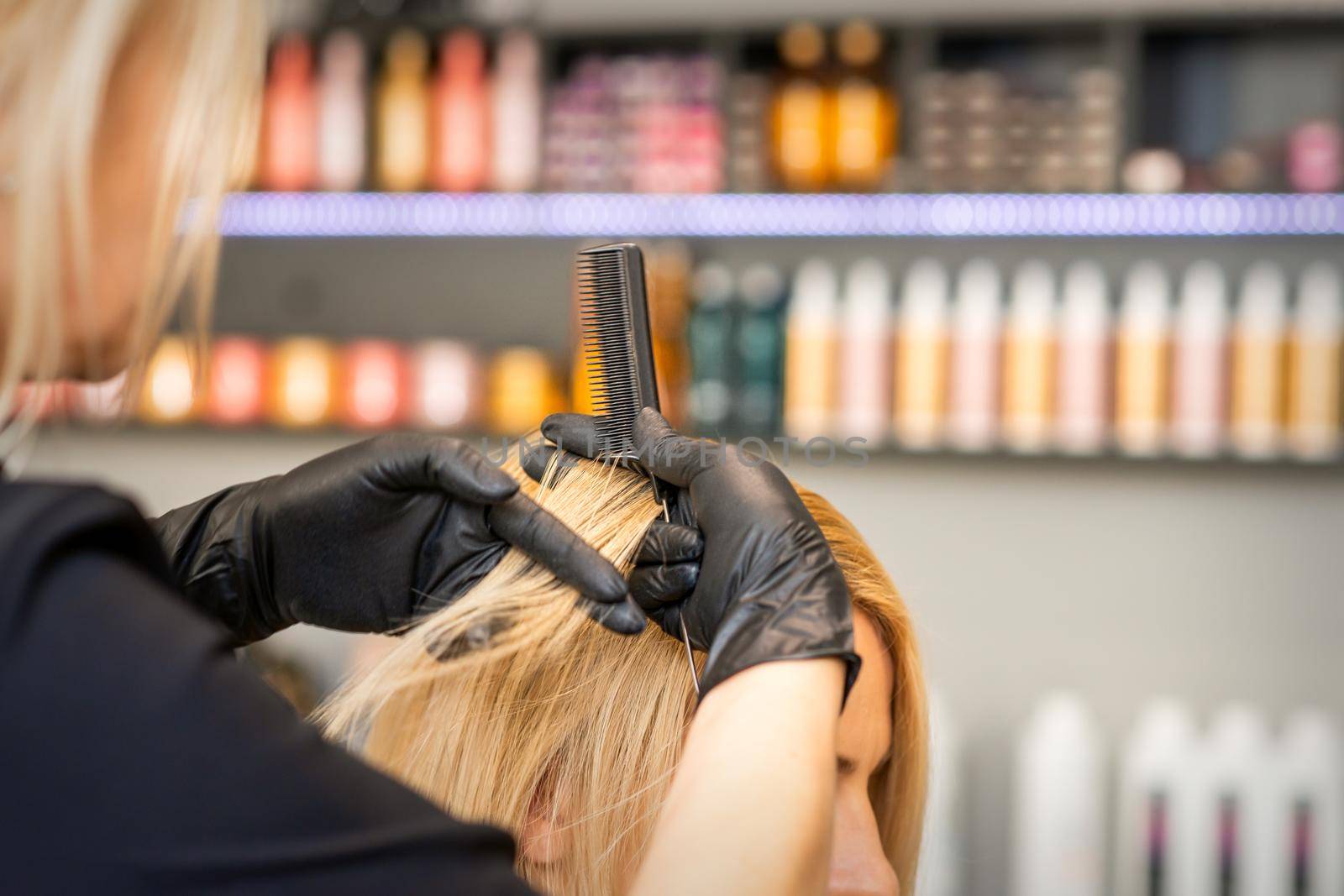 Hairdresser combing client's female hair before dyeing hair in a hair salon