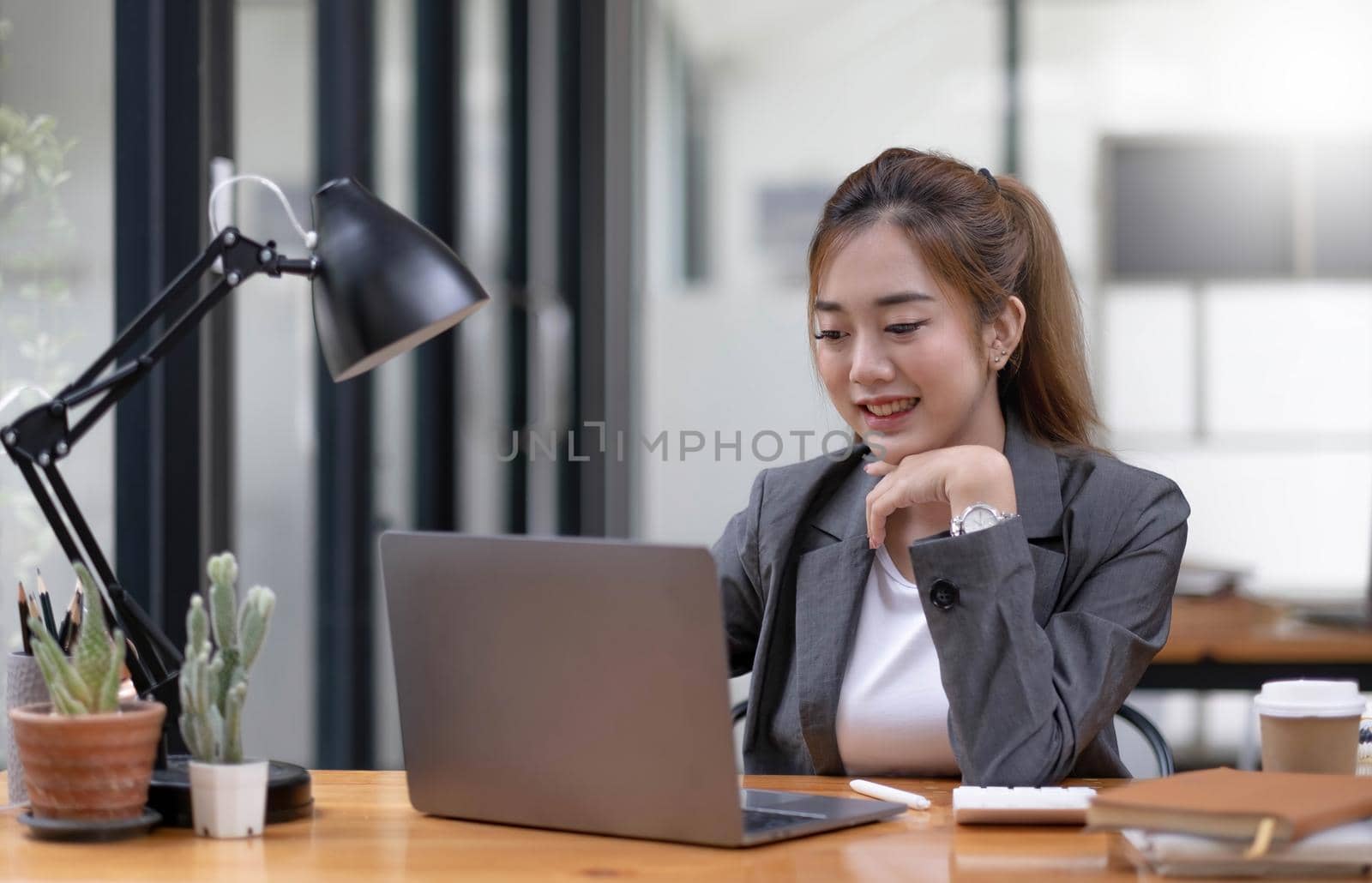 Young asian businesswoman beautiful charming smiling and using laptop computer in office. by wichayada