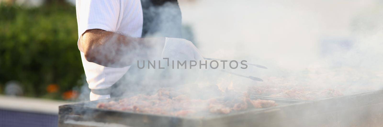 Male chef preparing barbecue on grill in restaurant closeup by kuprevich