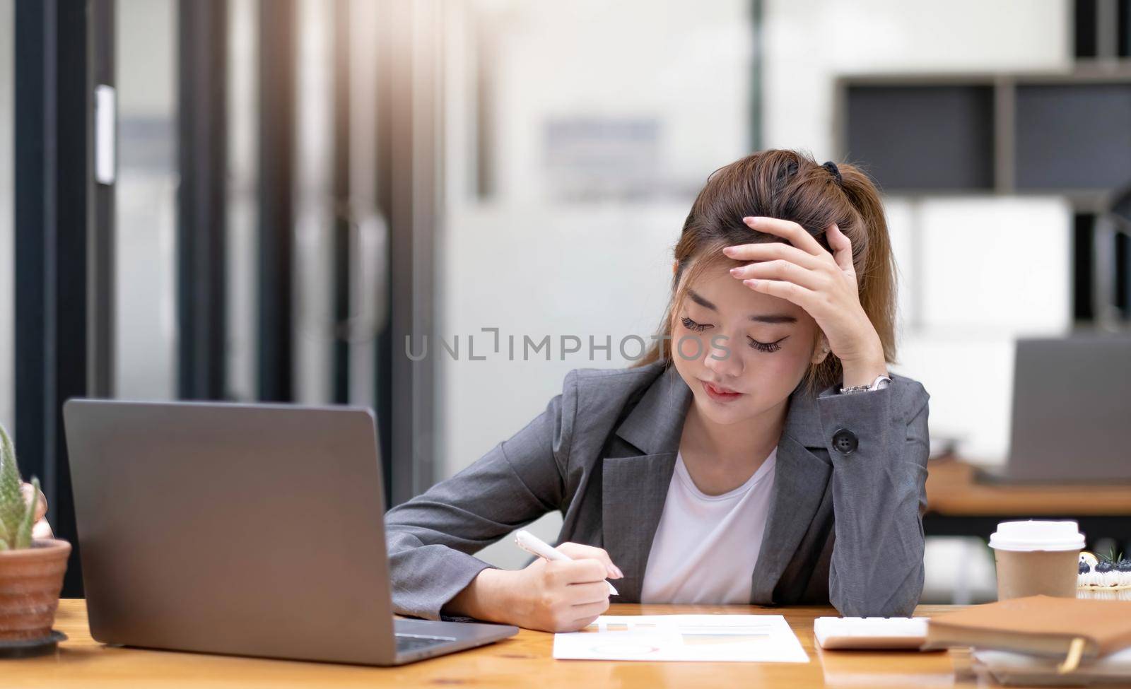 Asian woman who is tired and overthinking from working with a tablet at the office