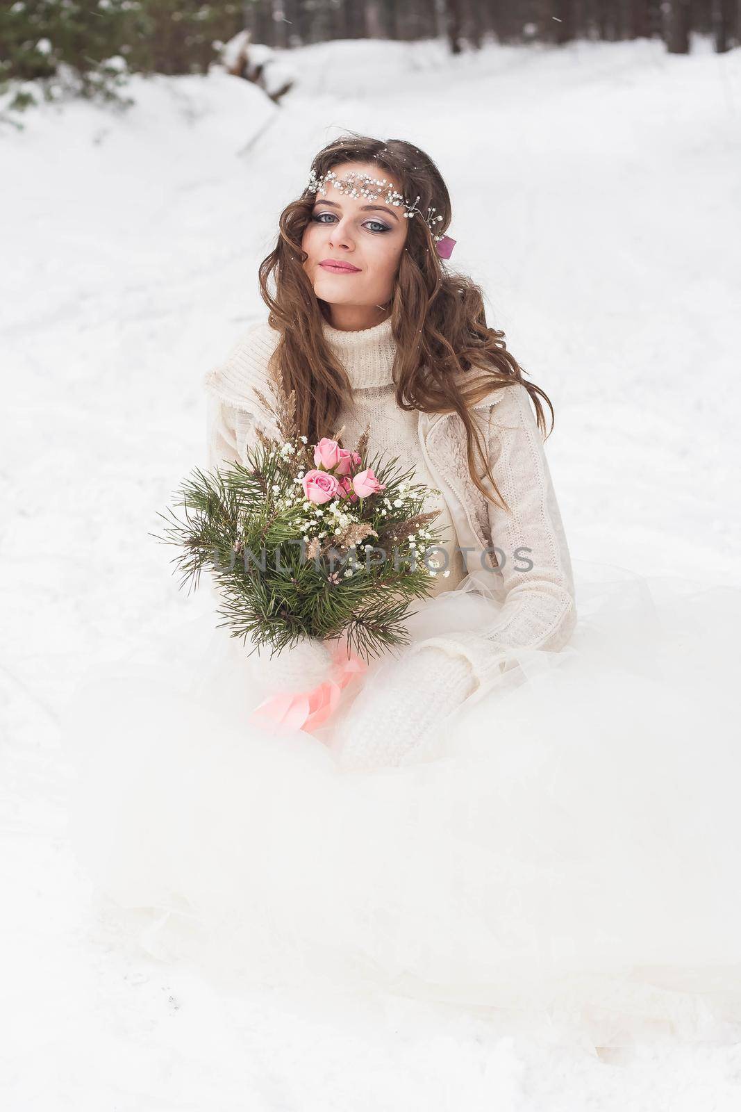 Beautiful bride in a white dress with a bouquet in a snow-covered winter forest. Portrait of the bride in nature.Beautiful bride in a white dress with a bouquet in a snow-covered winter forest. Portrait of the bride in nature.