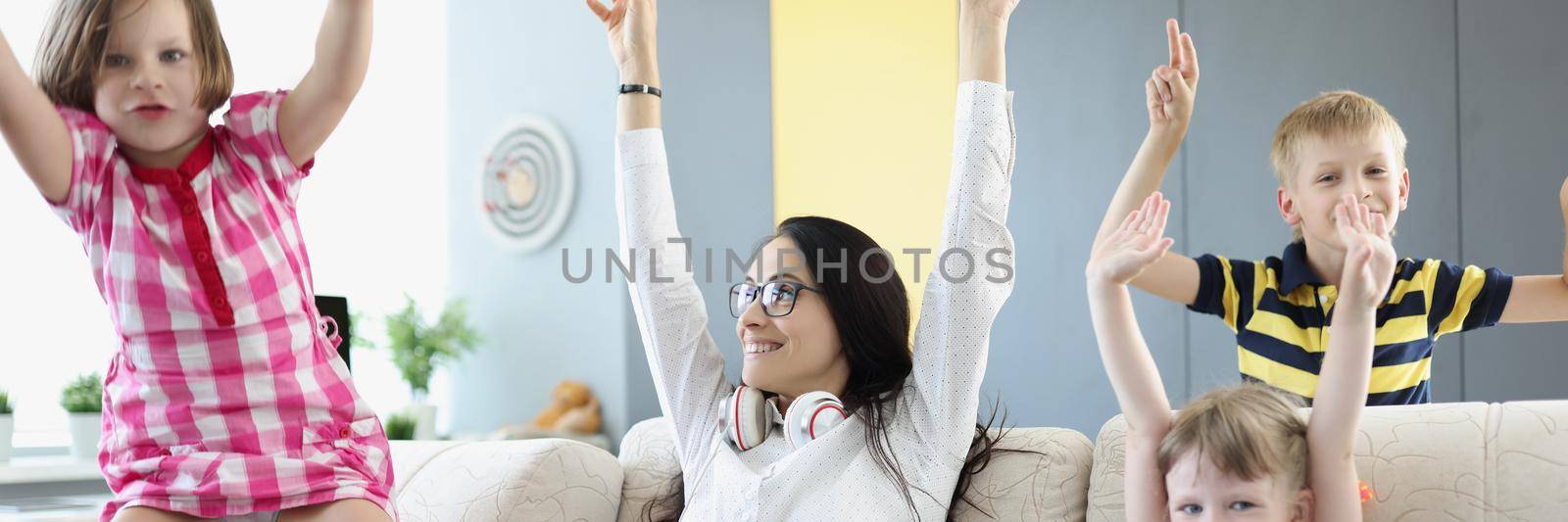 Woman with laptop and children rejoicing and raising their hands up at home by kuprevich