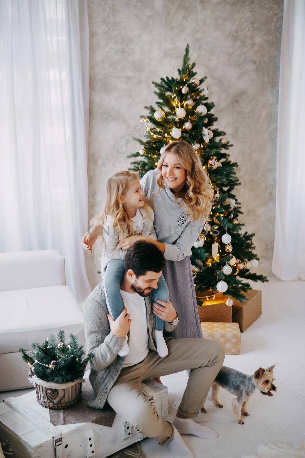 Happy family: mom, dad and pet. Family in a bright New Year's interior with a Christmas tree by Annu1tochka