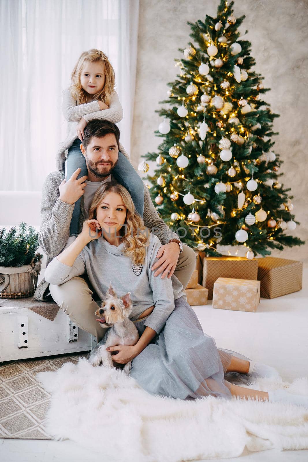 Happy family: mom, dad and pet. Family in a bright New Year's interior with a Christmas tree.