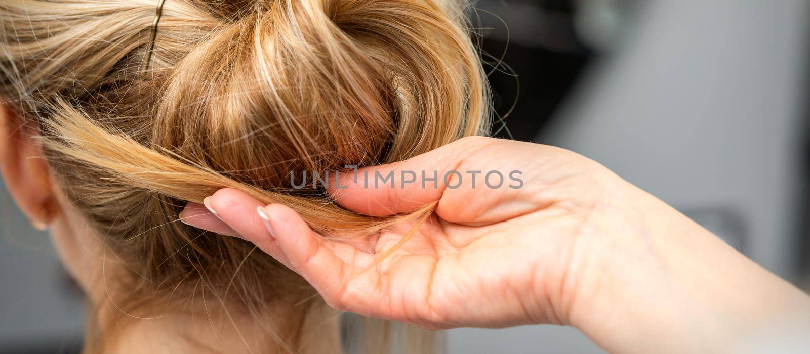 Close up of hands of female hairdresser styling hair of a blonde woman in a hair salon