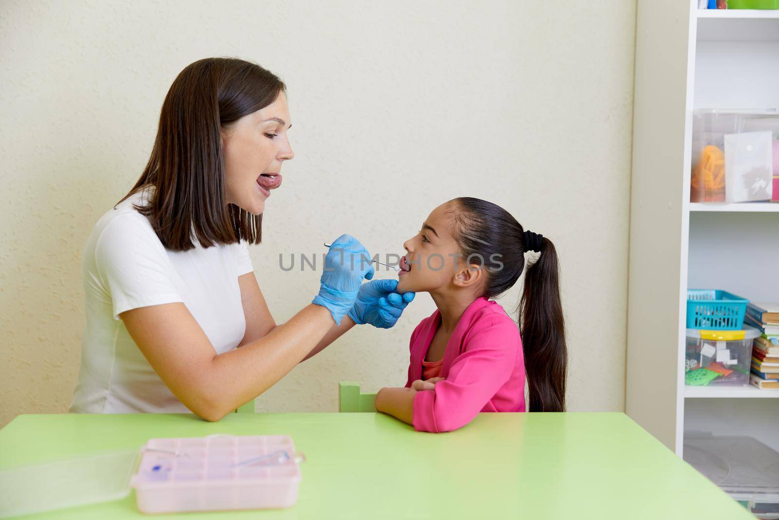 Speech therapist working with little girl in office training correct pronunciation