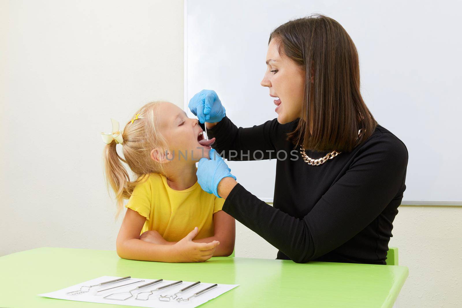 Speech therapist working with little girl in office training pronunciation by Mariakray