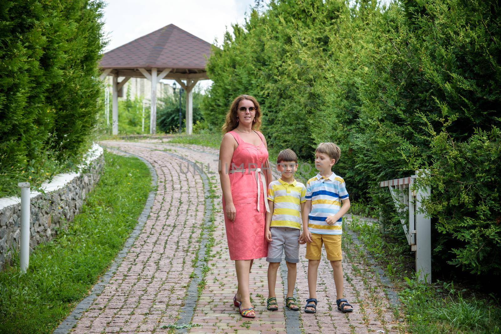 Young woman having fun playing in the park with their children. Boys of primary school age. The family is surrounded by picturesque plants. Games outdoor useful to all.