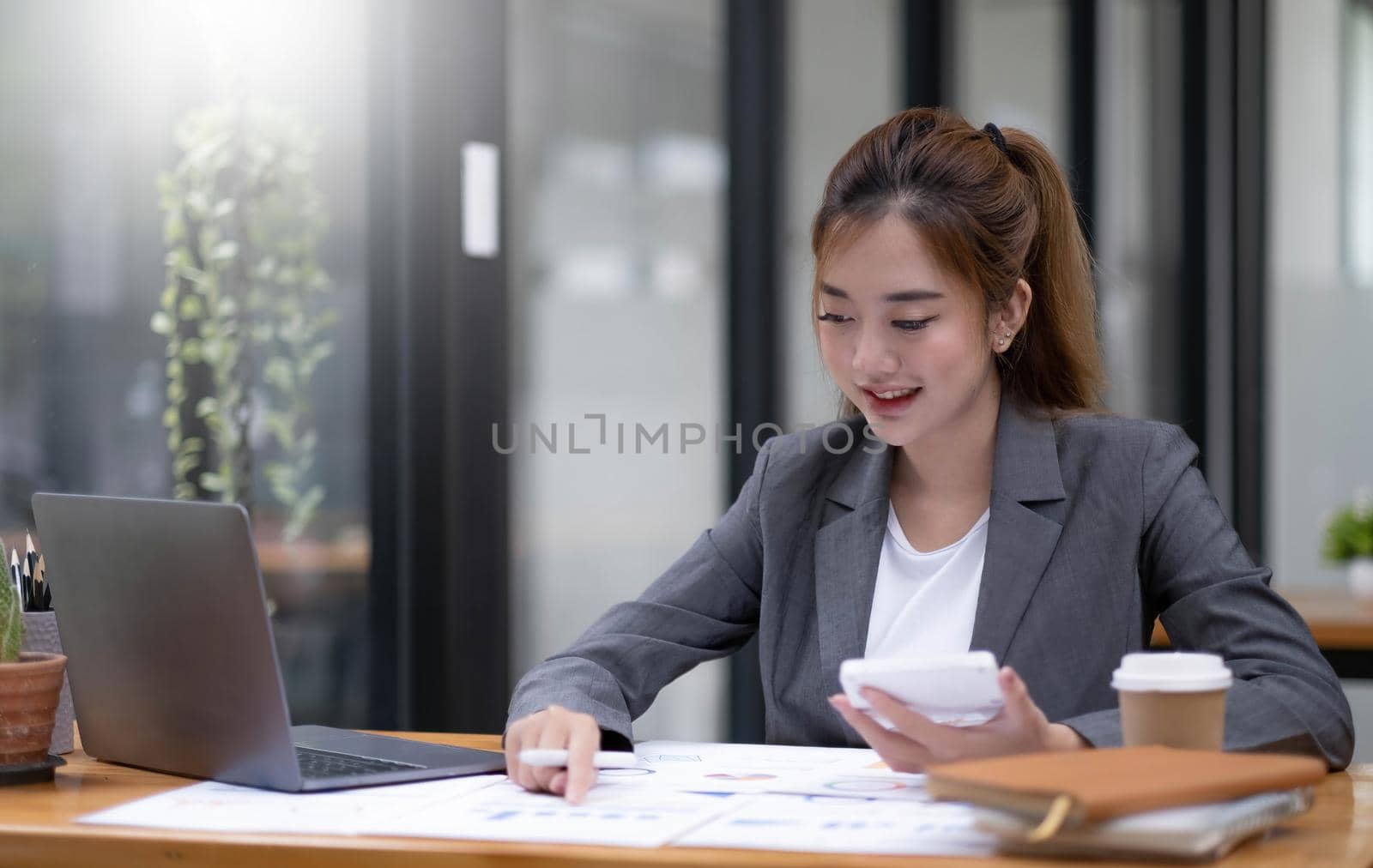 Pretty and charming asian businesswoman sitting happily smiling with laptop computer in the office..