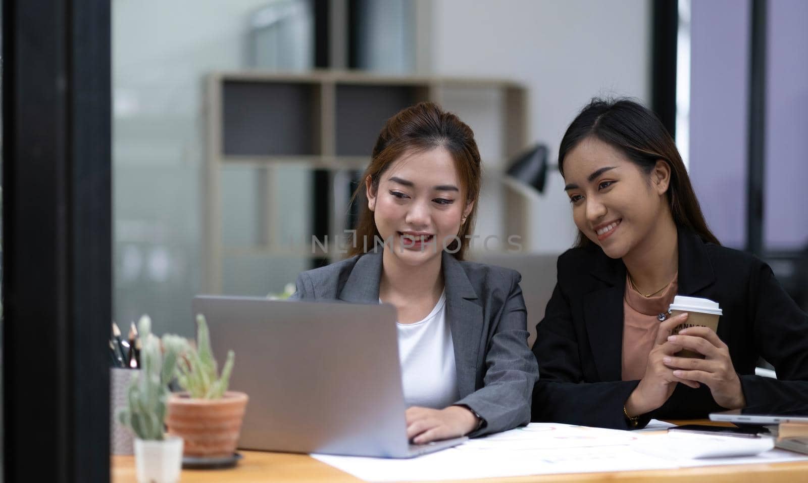 Two young Asian business woman talk, consult, discuss working with new startup project idea presentation analyze plan marketing and investment in the office. by wichayada