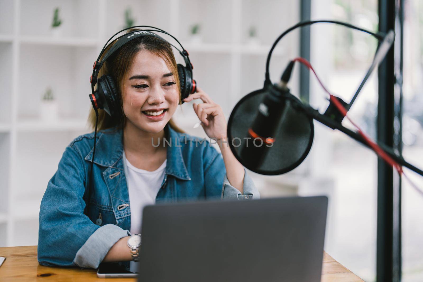 Young asian woman makes a podcast audio recording at home