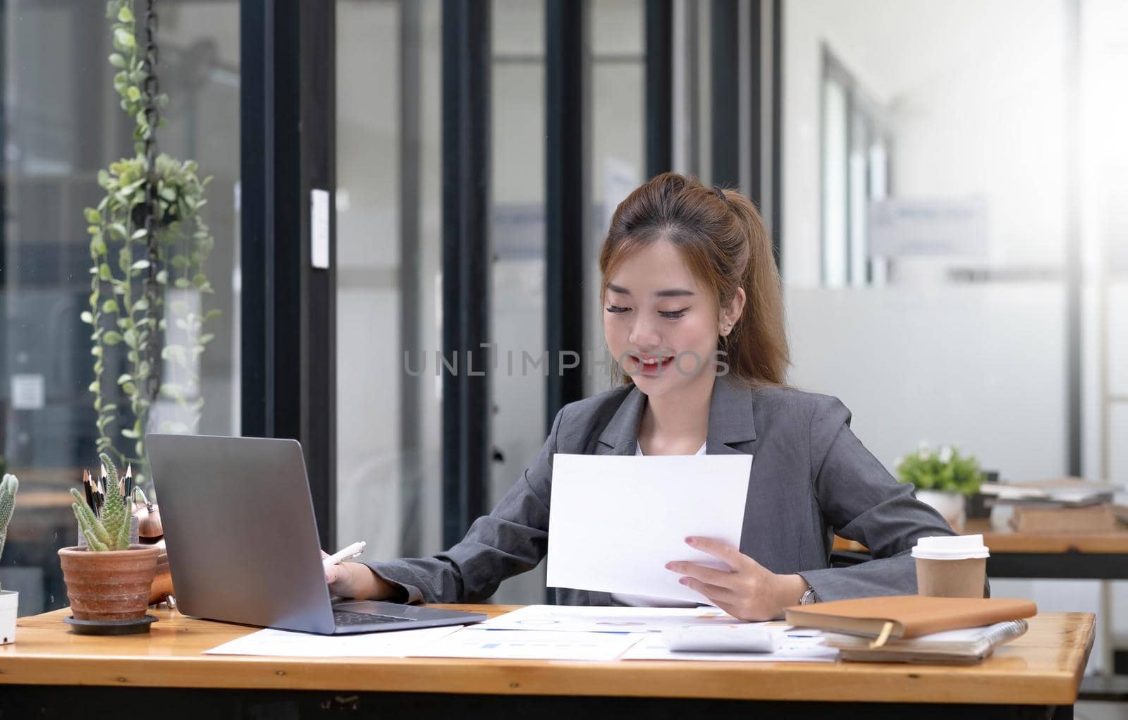 Beautiful Asian businesswoman work using a tablet and a laptop with documents placed at the office..