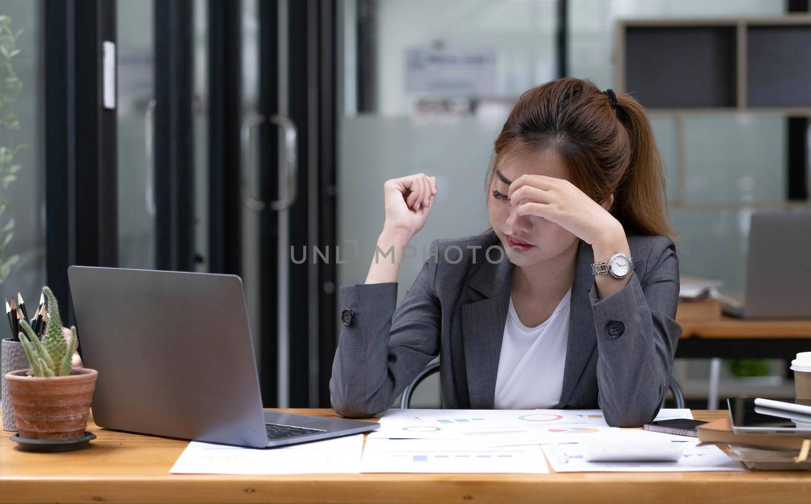 Asian woman who is tired and overthinking from working with a tablet at the office